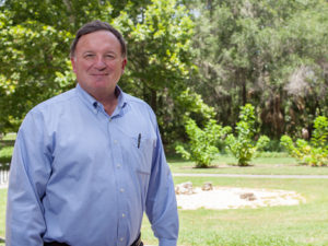 Man in blue shirt with trees in the background